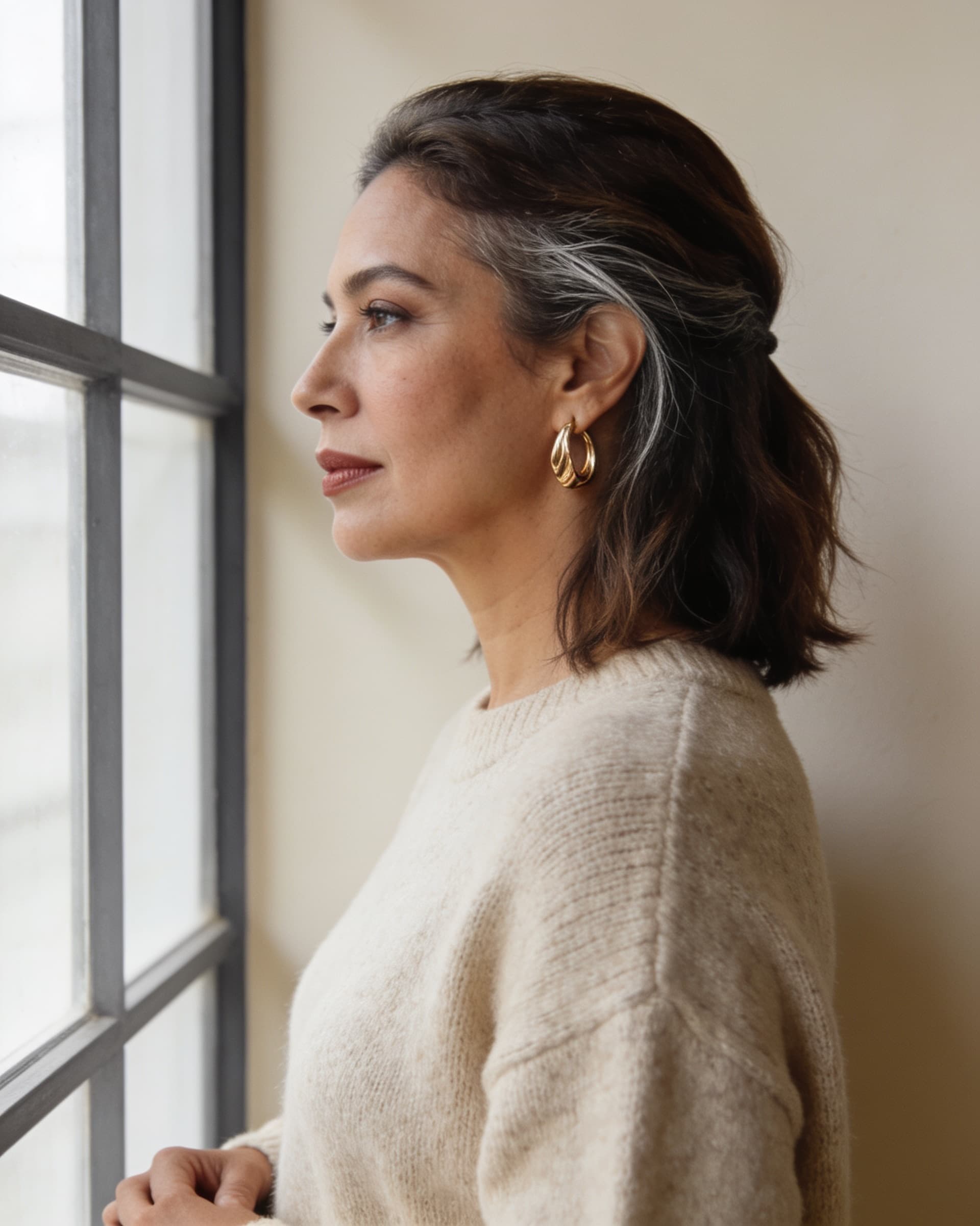 Perfil de una mujer con aretes de aro dorados de forma escultórica