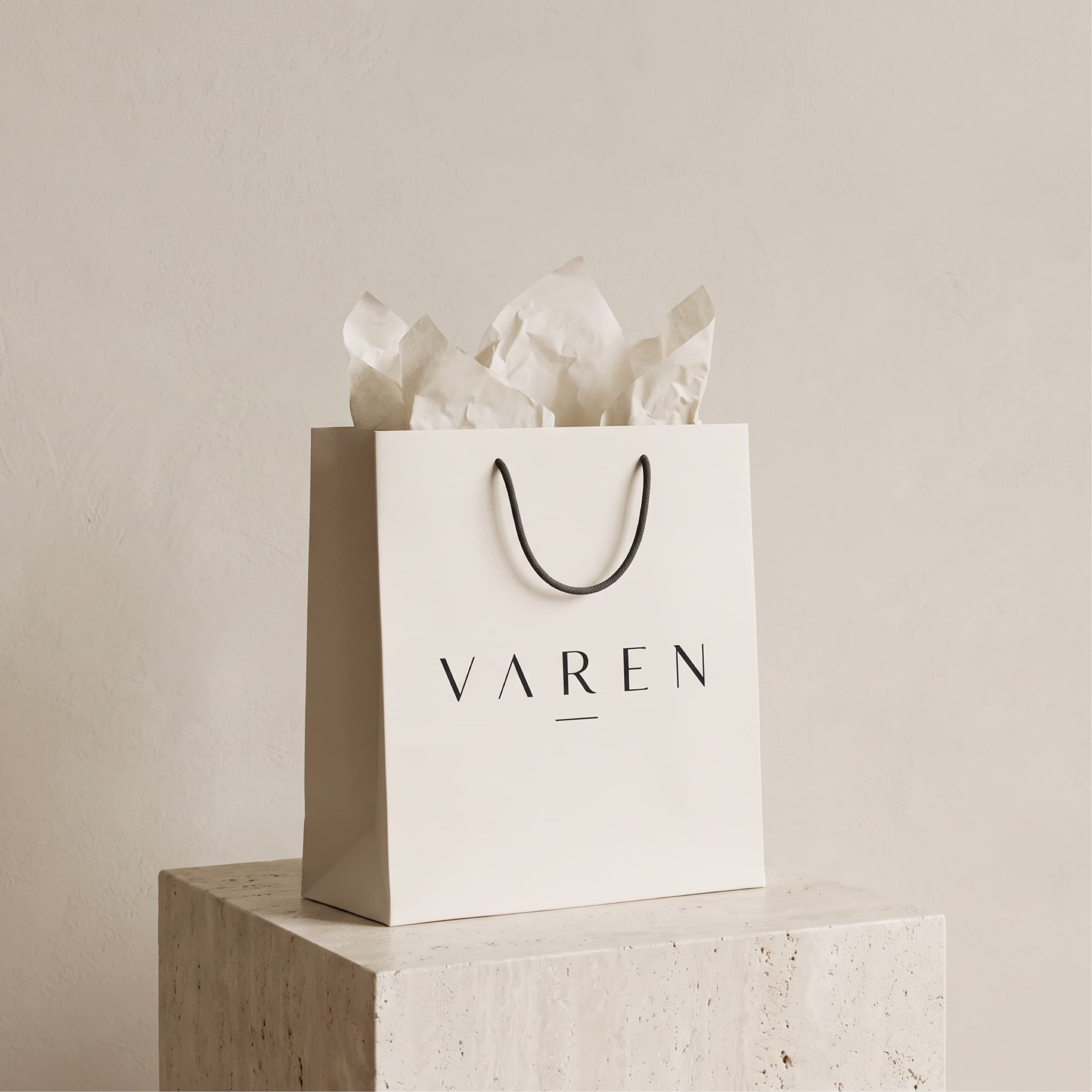 Bolsa de compras ivory con el logotipo VAREN sobre un pedestal de piedra